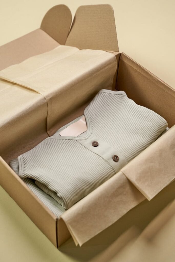 A neatly folded green knit garment in eco-friendly packaging box with tissue paper.